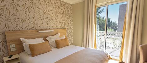 A hotel room with a large bed, a nightstand, a chair, and a balcony with a view.
