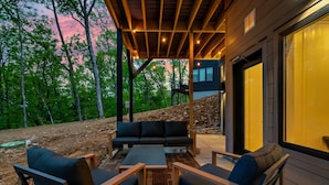 An outdoor patio with a wooden deck, a black sofa, and a coffee table.