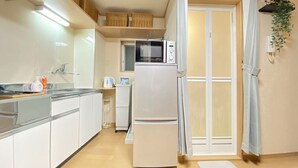 A modern kitchen with white cabinets, a microwave, a refrigerator, and a window with a view.
