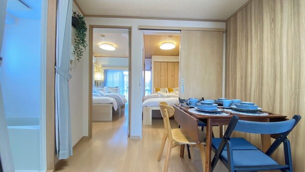 A compact hotel room with a dining area, a bed, and a bathroom visible through an open door.