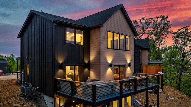 A modern two-story house with a deck and large windows.