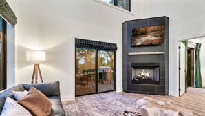 A modern living room with a fireplace, a sofa with cushions, a large rug, and a wooden coffee table.