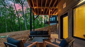 An outdoor patio with a wooden deck, a black sofa, and a coffee table.