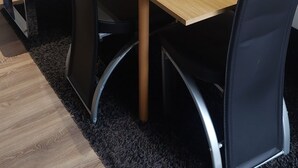 A chair with a black seat and metallic frame, a wooden table, and a black carpeted floor. - Apartment terasse Le Barcarès  (Le Barcarès)