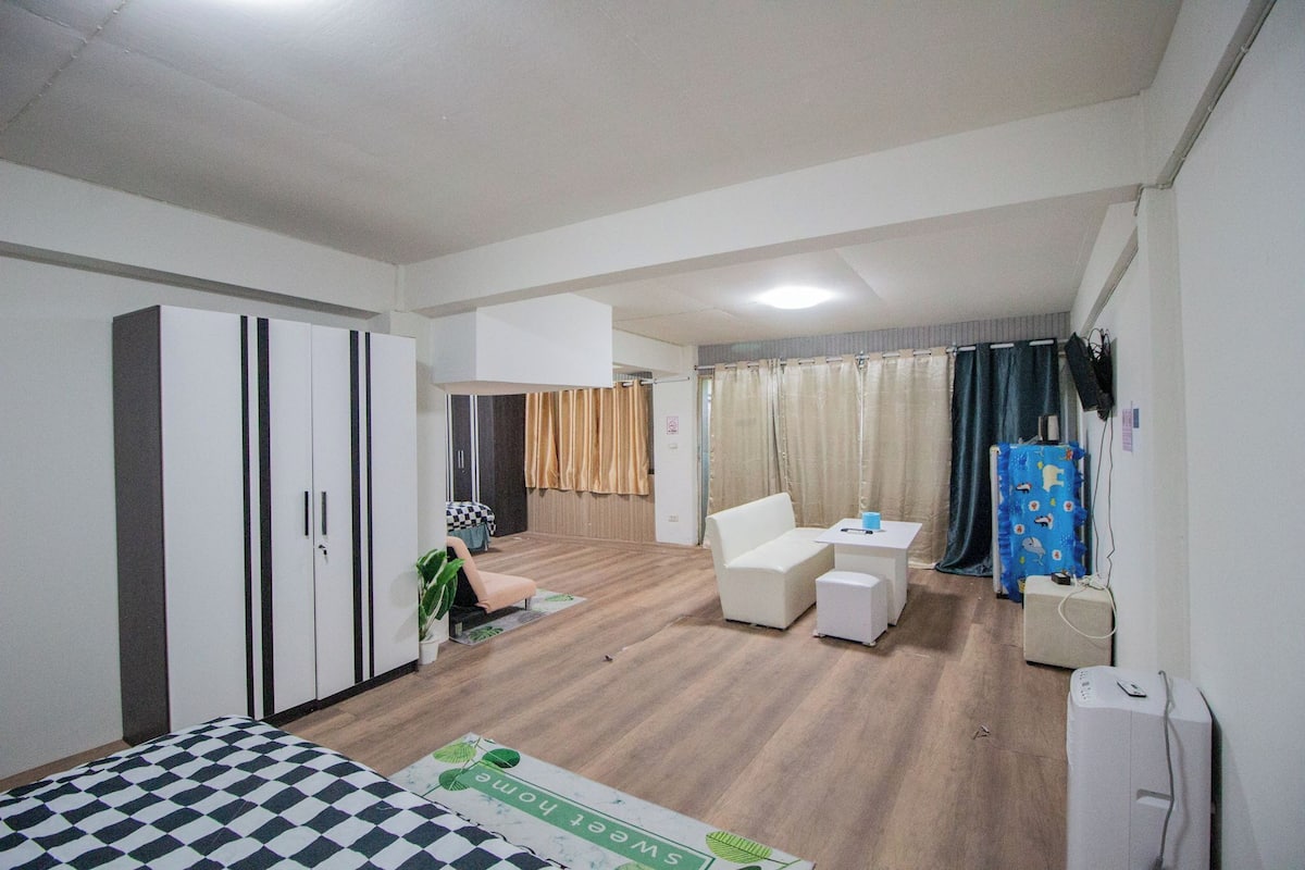 A hotel room with a bed, wardrobe, seating area, and a small table.