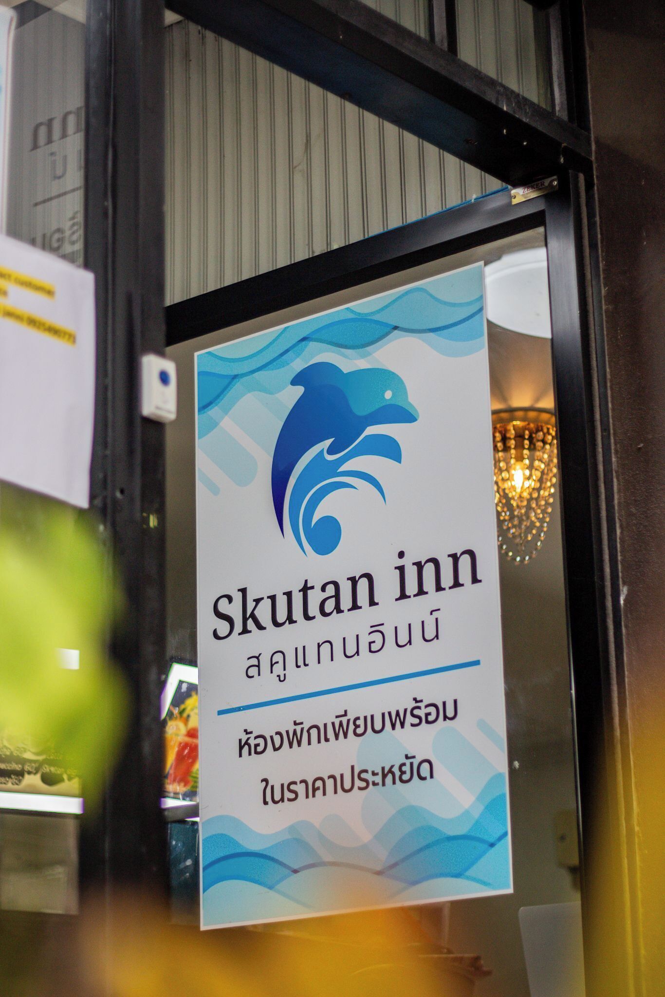 A sign for Skutan Inn with a dolphin logo and Thai text.