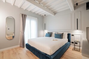 A modern bedroom with a large bed, a mirror, a bedside table, and a window with curtains. - Maison Ginori Guelfa (Florence)