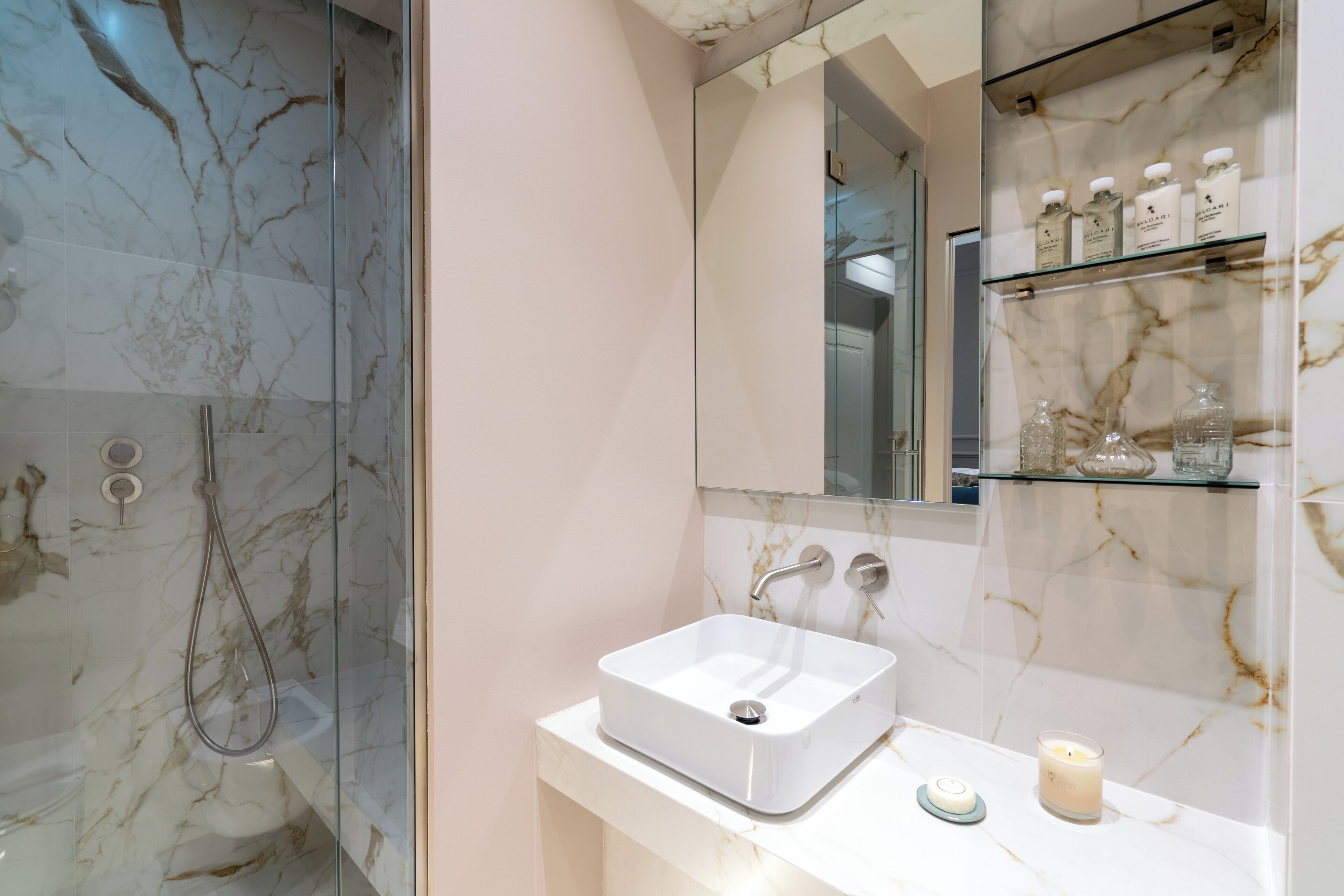 A bathroom with a glass-enclosed shower, a white sink, and a mirror above it.