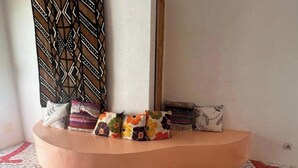 A corner seating area with a curved bench and a variety of colorful pillows. - 1 Bedroom Bed & breakfast in GuÃ©rÃ©o (Guéréo)