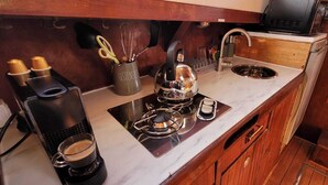 A compact kitchen with a gas stove, a sink, and a coffee maker.