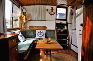 Un intérieur chaleureux avec un banc en bois, une table garnie de fruits et une horloge murale.