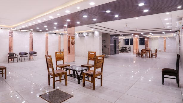 A spacious indoor area with multiple seating arrangements, including tables and chairs, and a polished tiled floor. - The Ansal (Greater Noida)