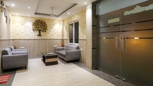 A modern living room with a sofa set, a coffee table, and a large metallic cabinet. - The Ansal (Greater Noida)