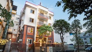 A multi-story residential building with balconies, a gated entrance, and a tree in front. - The Ansal (Greater Noida)