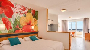Een hotelkamer met een groot bed, een zithoek en uitzicht op zee.