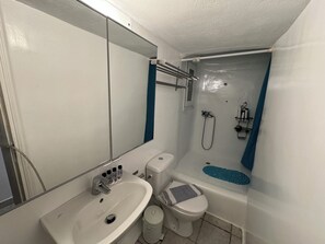 A compact bathroom with a sink, toilet, and shower.