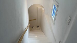 Una escalera estrecha con paredes blancas y barandilla de madera.