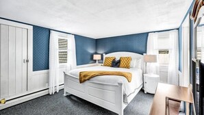Une chambre avec un lit blanc, des murs bleus et un tapis gris.