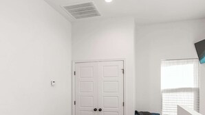 A bedroom with a bed, a chair, a window, and a door.