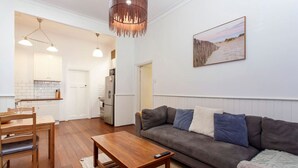 A modern living room with a sofa, a wooden coffee table, and a dining area with a table and chairs.