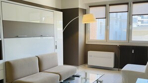 A modern living room with a sofa, a glass coffee table, a lamp, and a radiator. - Modern and bright studio (Cannes)