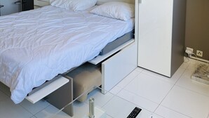A modern bedroom with a bed, a desk, and a lamp. - Modern and bright studio (Cannes)