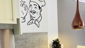 A kitchen with a hanging pendant light, a wall-mounted drawing, a small Christmas tree, and a spice rack. - Modern and bright studio (Cannes)