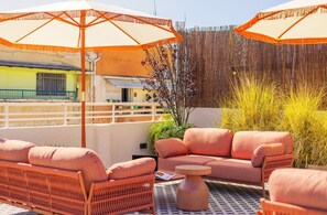 An outdoor seating area with wicker furniture and orange umbrellas.
