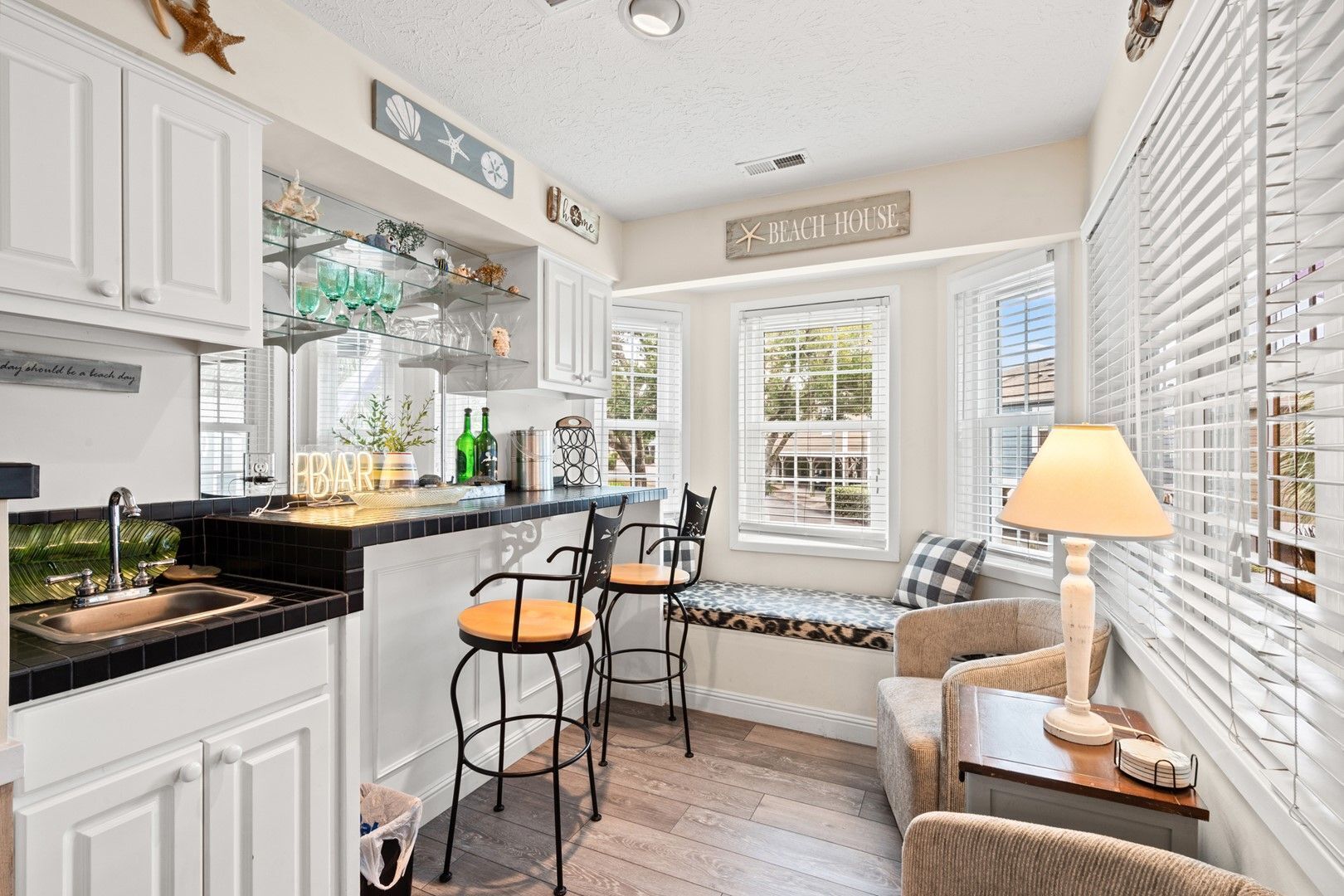 A kitchen with a bar area, white cabinetry, and a sign reading "Beach House".