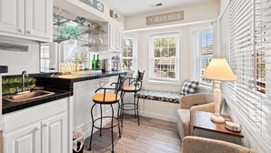 A kitchen with a bar area, white cabinetry, and a sign reading "Beach House". - Escape to Beach Bum 5 - Your Ultimate Family Beach Retreat in Shore Drive (Myrtle Beach)