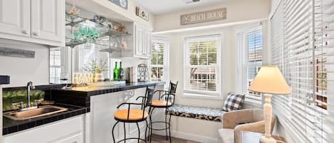 A kitchen with a bar area, white cabinetry, and a sign reading "Beach House".