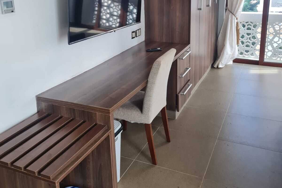 A modern room with a wooden desk, a TV, and a chair.