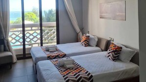 A hotel room with two beds, a ceiling fan, a large window with a view, and a balcony. - Luxury Beachfront Apartments (Mombasa)