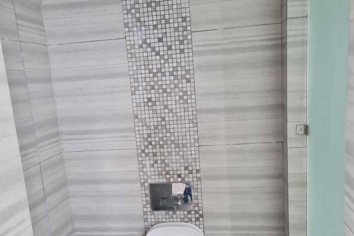 A small, tiled bathroom with a toilet, a bidet, and a toilet brush.