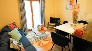 Un salon comprenant un canapé, une table basse, un téléviseur et une table à manger avec des chaises.