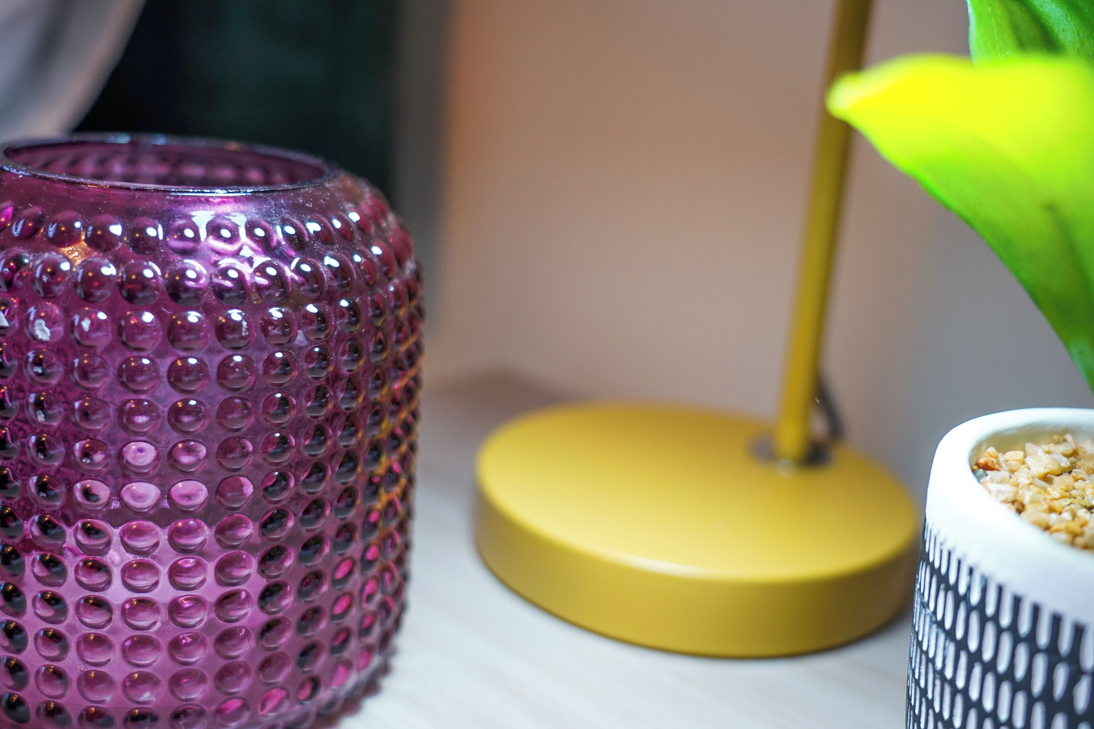A pink textured vase, a yellow base, and a patterned container with grains.