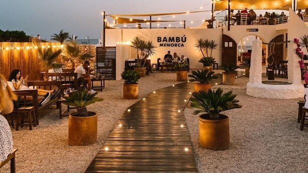A restaurant named Bambú Menorca with outdoor seating and a wooden pathway leading to the entrance. - HOTEL GULMOHAR PLAZA BY AUROVILLE ENT (Chandauli)