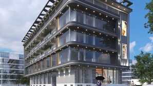 A modern multi-story building with a curved facade, large windows, and a prominent entrance with a glass door. - HOTEL GULMOHAR PLAZA BY AUROVILLE ENT (Chandauli)