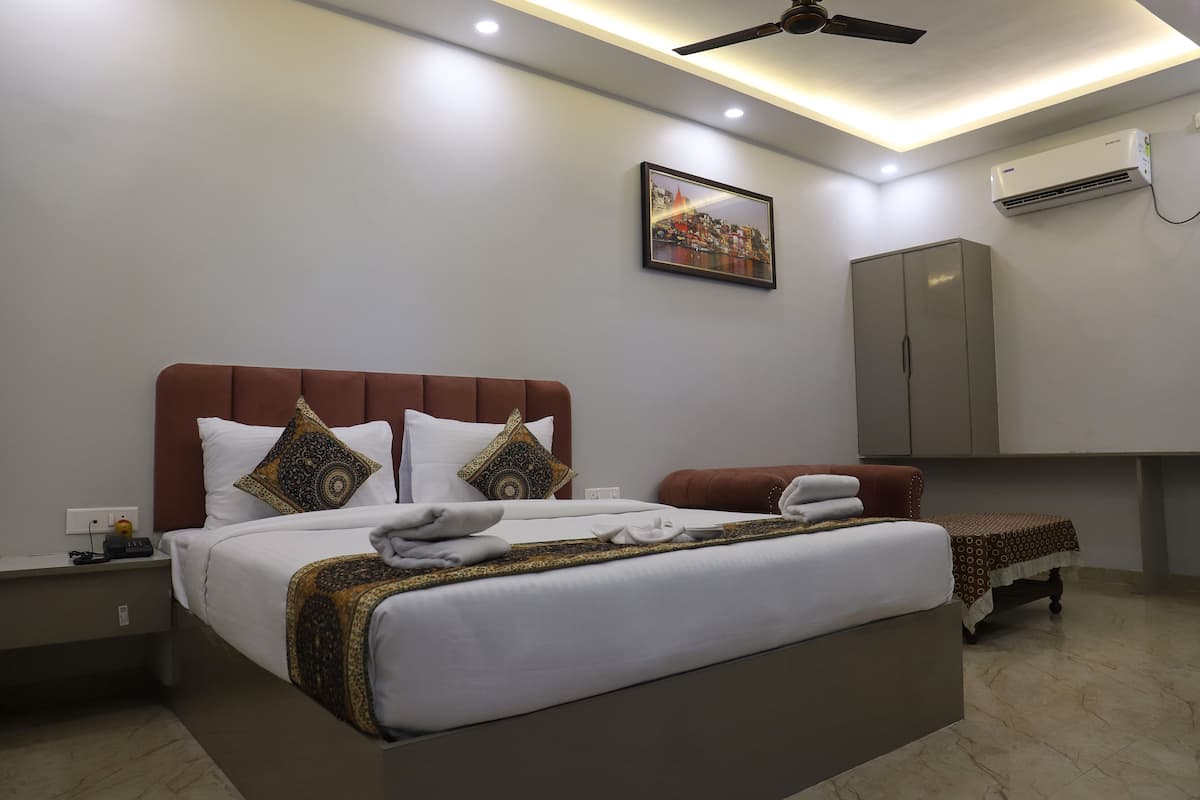 Une chambre d’hôtel moderne avec un grand lit, un ventilateur de plafond, un appareil de climatisation et un tableau encadré au mur.