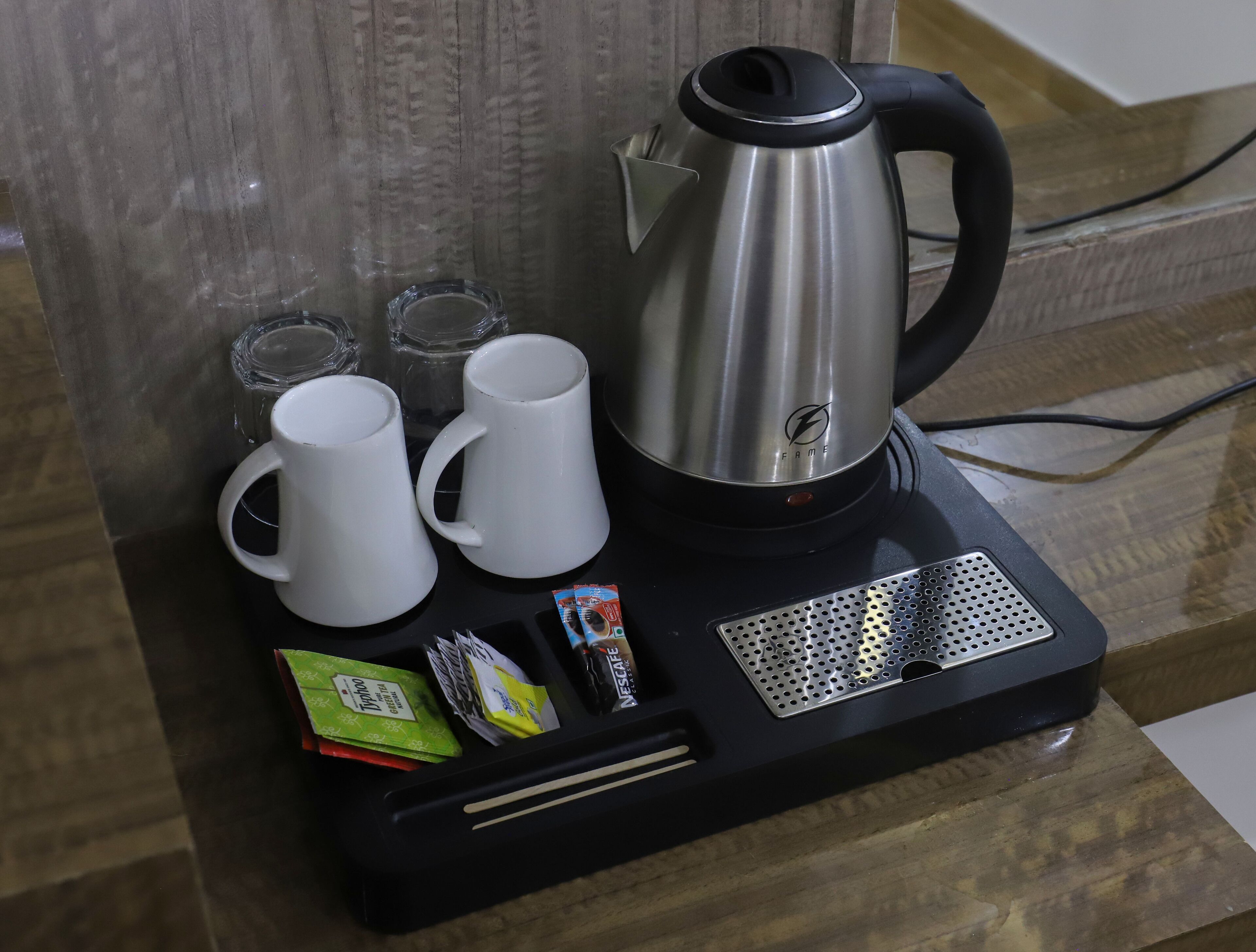 Una cafetera con dos tazas blancas y un termo sobre una bandeja negra.