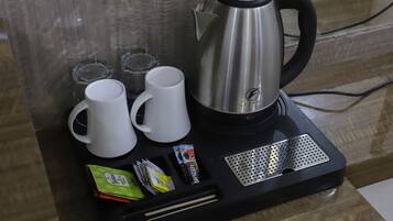Una cafetera con dos tazas blancas y un termo sobre una bandeja negra.