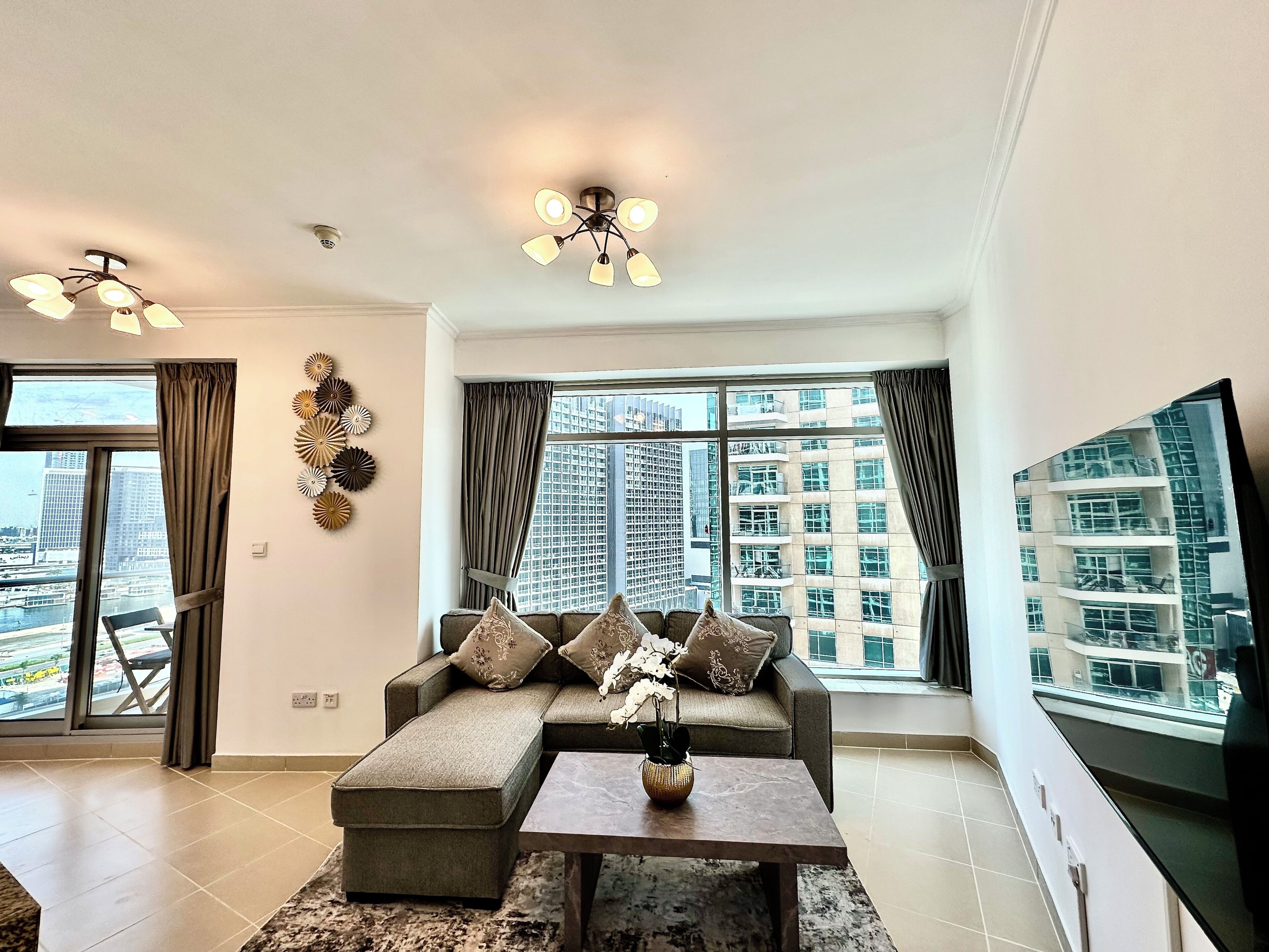 A modern living room with a sectional sofa, a coffee table, and a large window offering a city view.