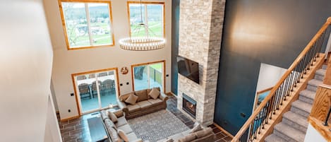 A spacious living area with a fireplace, a large window, and a staircase.
