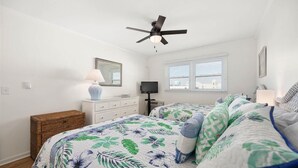A bedroom with a bed, a dresser, a television, a ceiling fan, and a window with blinds. - Windbreaker - Amazing Views From This 1 Bedroom Oceanfront Condo (Ocean City)