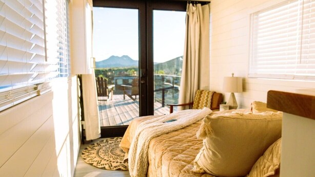 A bedroom with a bed, a view of the outdoors, and a balcony. - Somewhere in Texas Container Home (Alpine)