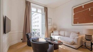 Un salon moderne avec un canapé, des fauteuils, une table basse et un téléviseur.