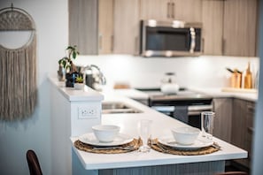 A modern kitchen with white countertops, a microwave, and wooden cabinets.