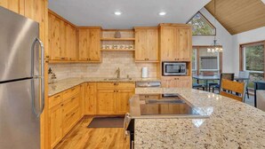 A modern kitchen with wooden cabinets, granite countertops, stainless steel appliances, and a large island. - Updated, great location, by Sharc and Village mall (Sunriver)