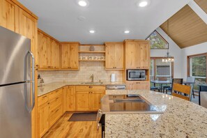 A modern kitchen with wooden cabinets, granite countertops, stainless steel appliances, and a dining area with a view. - Updated, great location, by Sharc and Village mall (Sunriver)