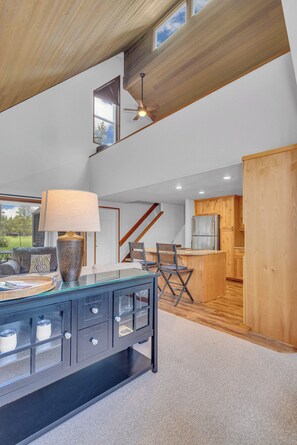 A modern interior with a glass-top dining table, wooden cabinets, and a kitchen area. - Updated, great location, by Sharc and Village mall (Sunriver)